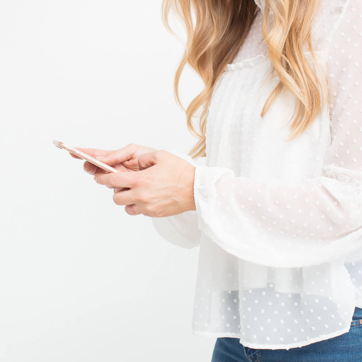 Blonde woman in white shirt holding a smartphone