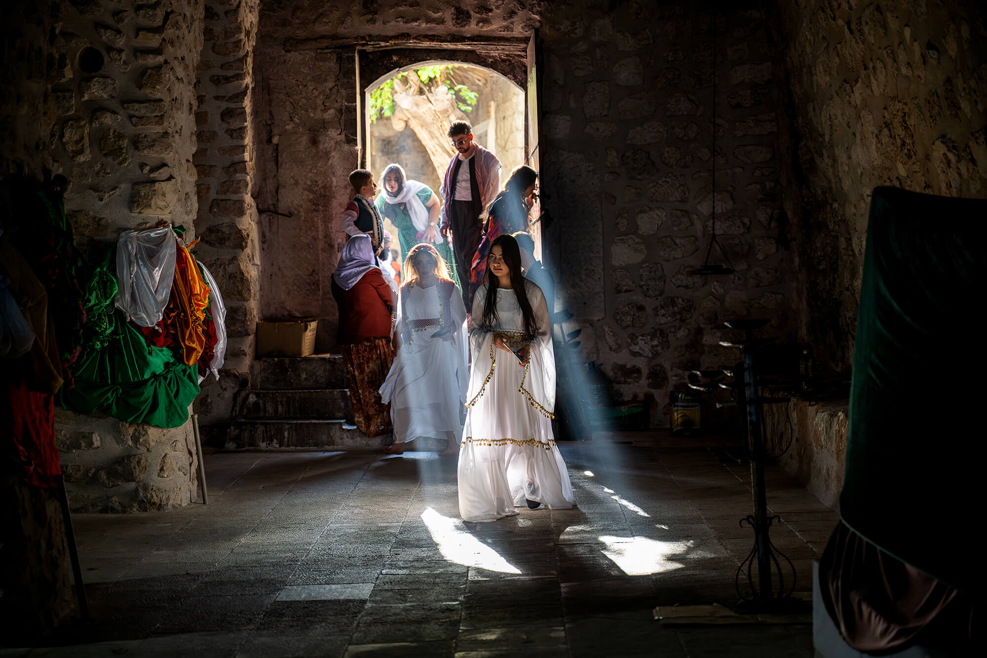People entering a building with a strong beam of light casting on a young woman wearing white