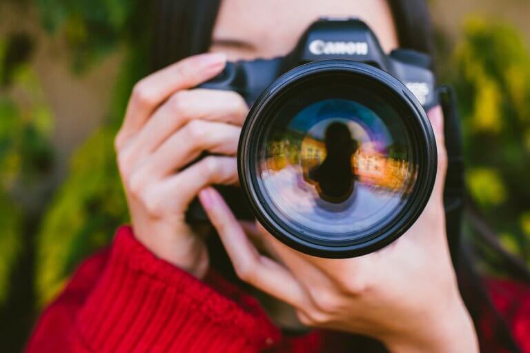 Female photographer holding a Canon camera up to her face