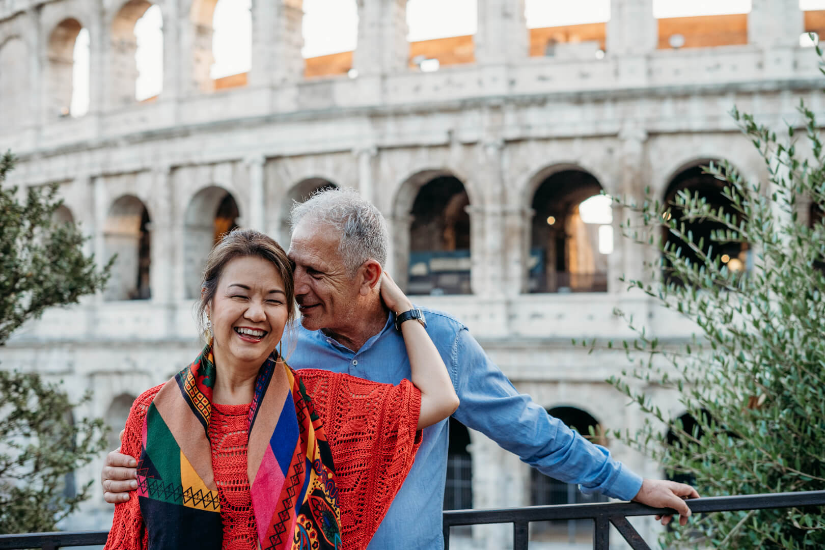 A couple stand together in front of the Colusseum in Rome